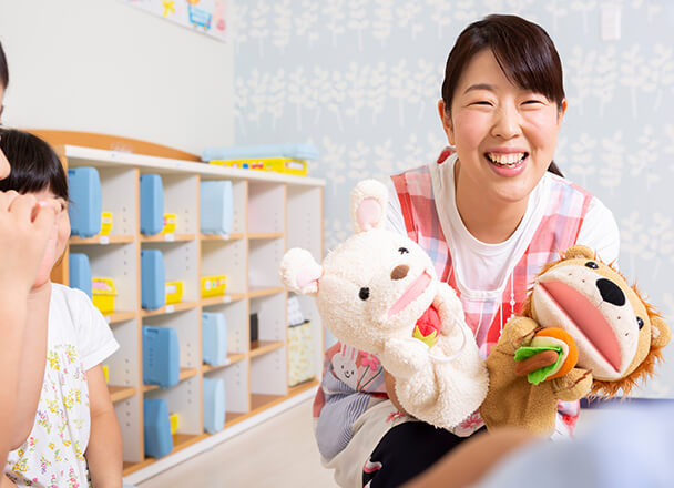 先生が園児にパペットで話しかけるイメージ